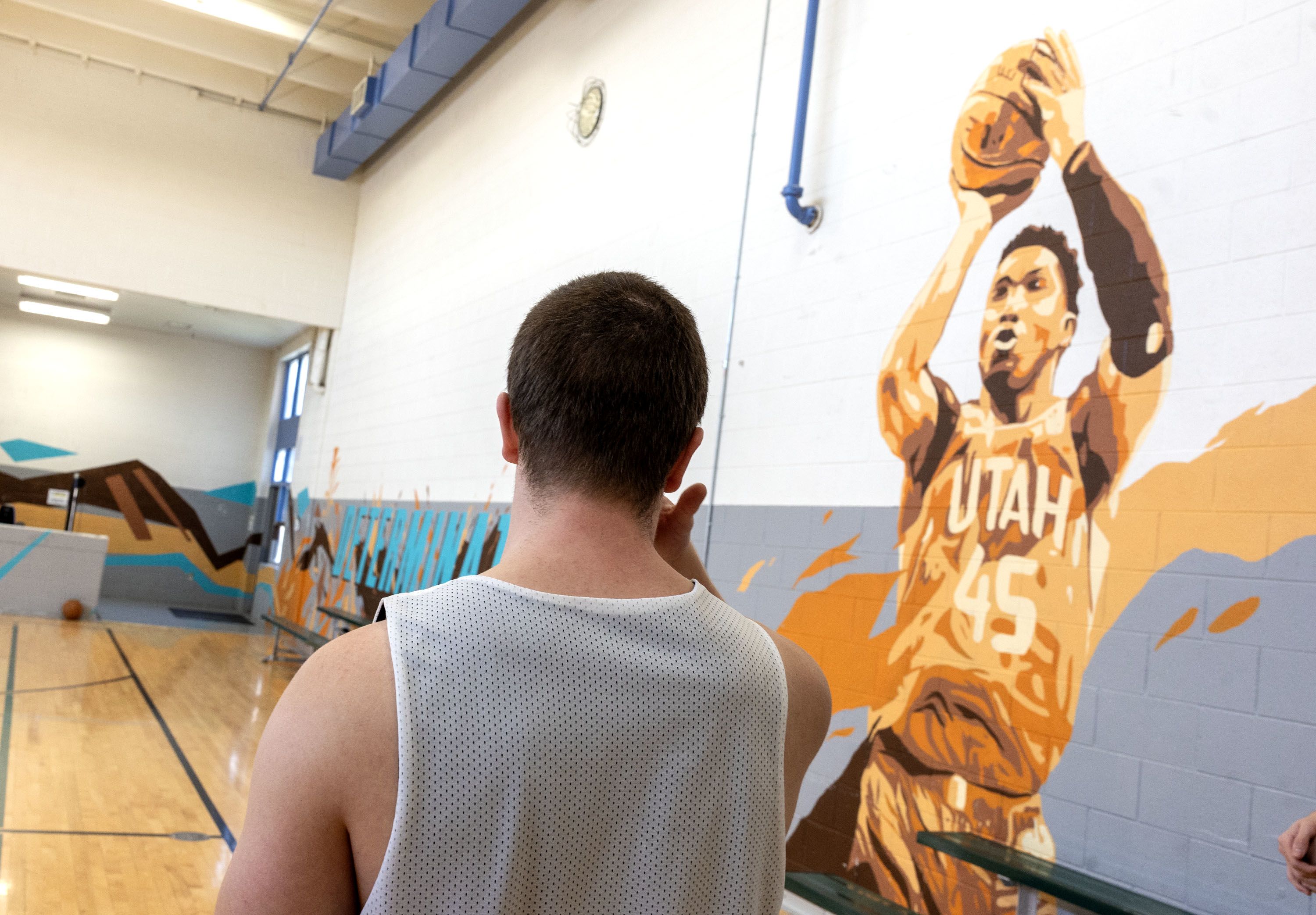 An incarcerated youth looks at a mural of former Utah Jazz basketball player Donovan Mitchell inside the gym at Decker Lake Youth Center.