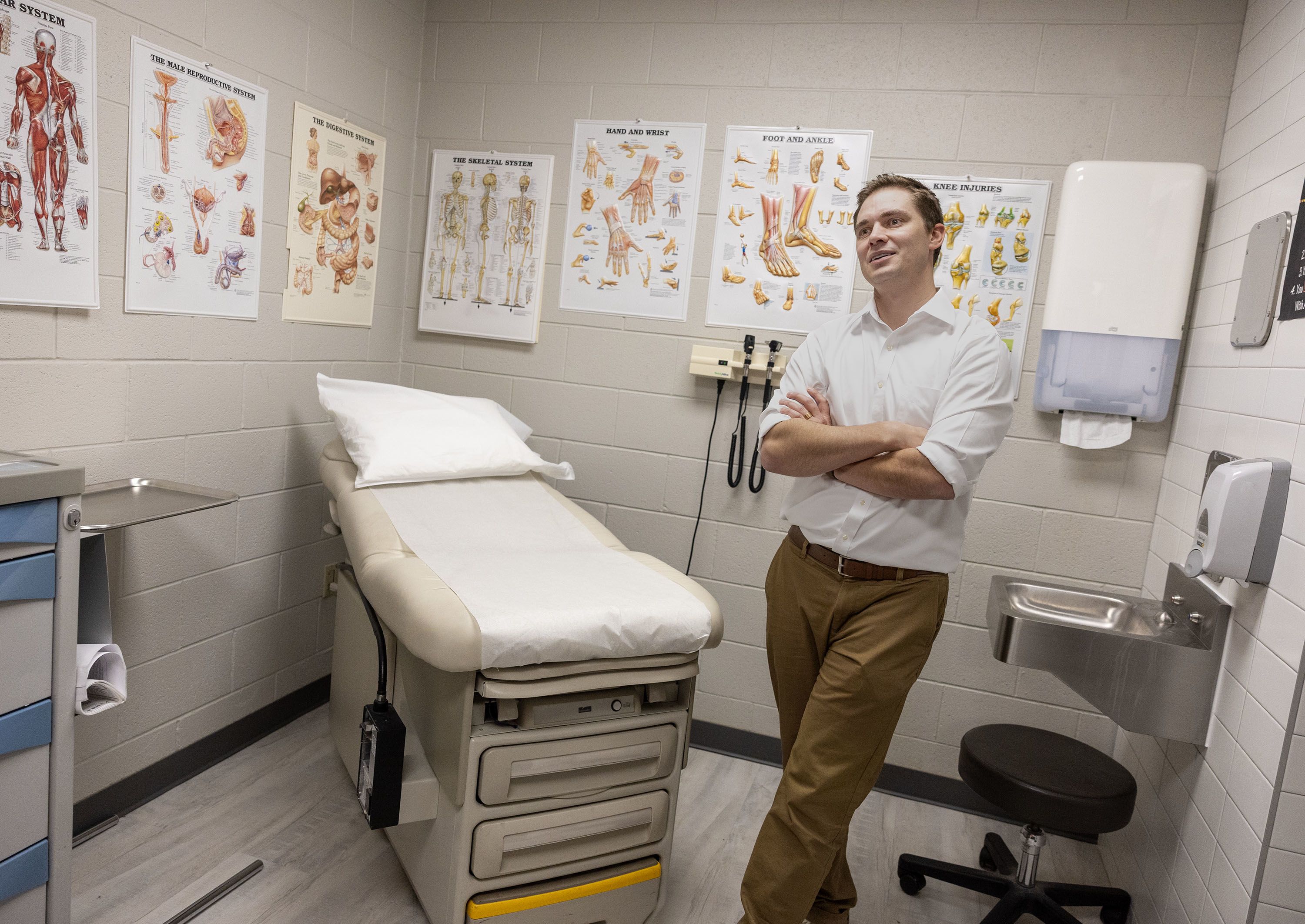 Tom Rowley, DNP, FNP-C, stands with arms folded inside an exam room at Decker Lake Youth Center.