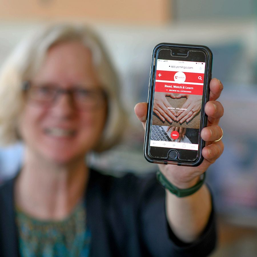Gwen Latendresse holding a phone whose screen displays the telehealth group program.