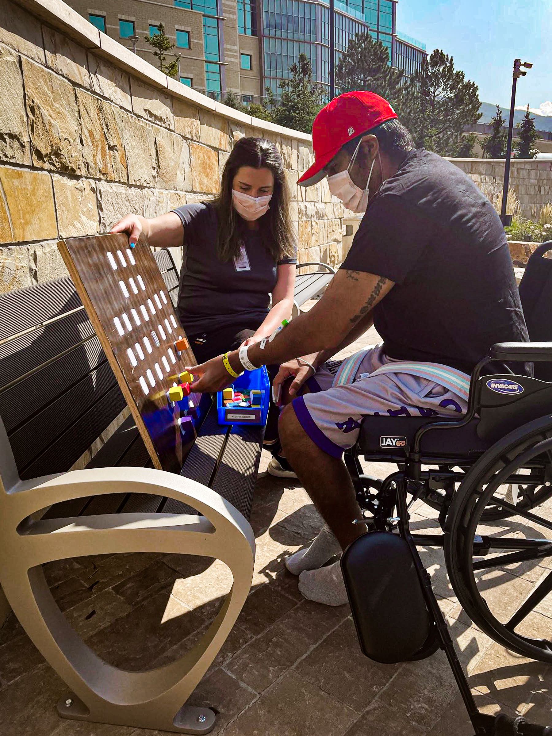 Manny sits in a wheelchair on a sunny day working on his therapy.