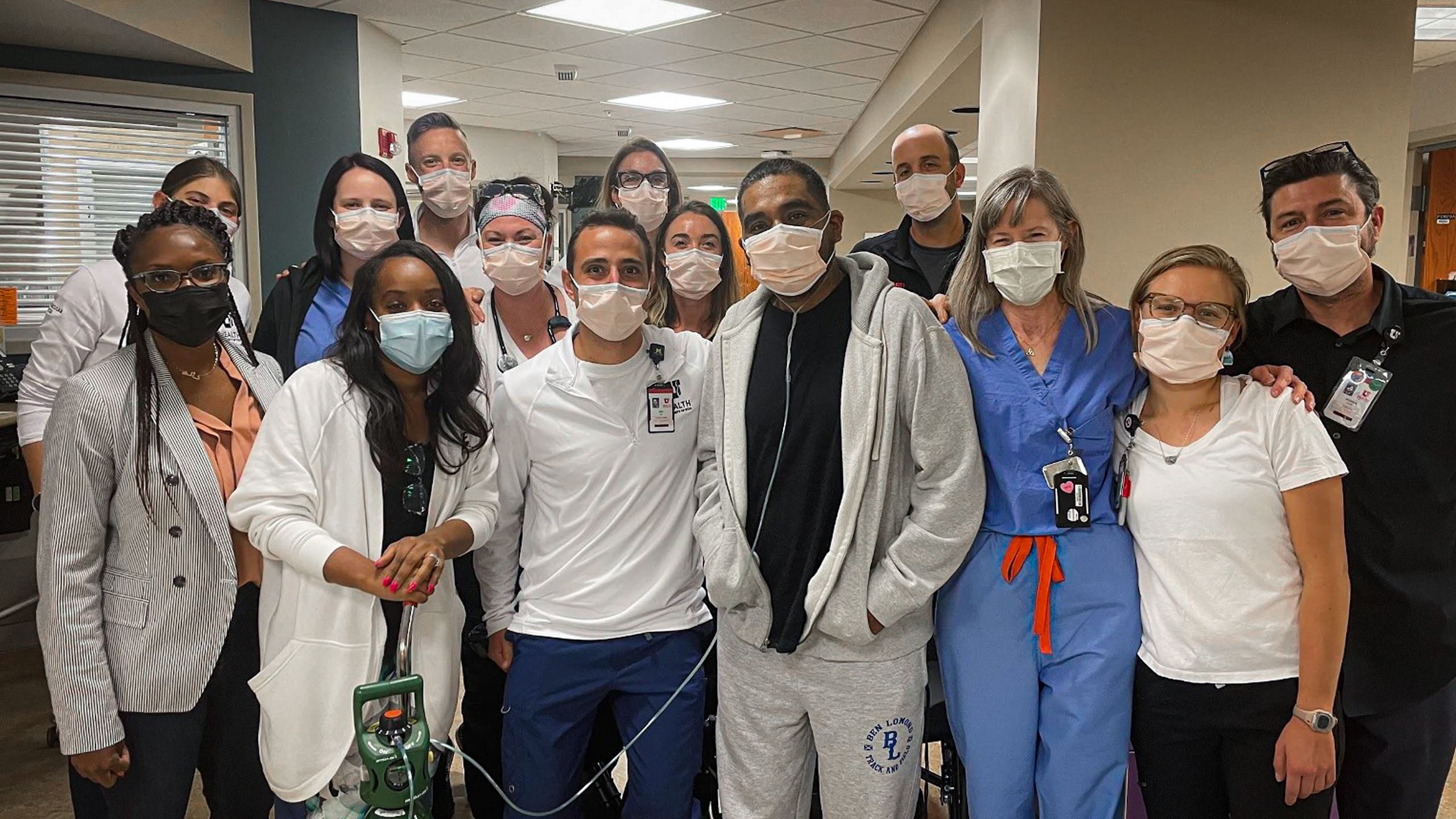Manny standing with staff in the hallway of the CVICU.