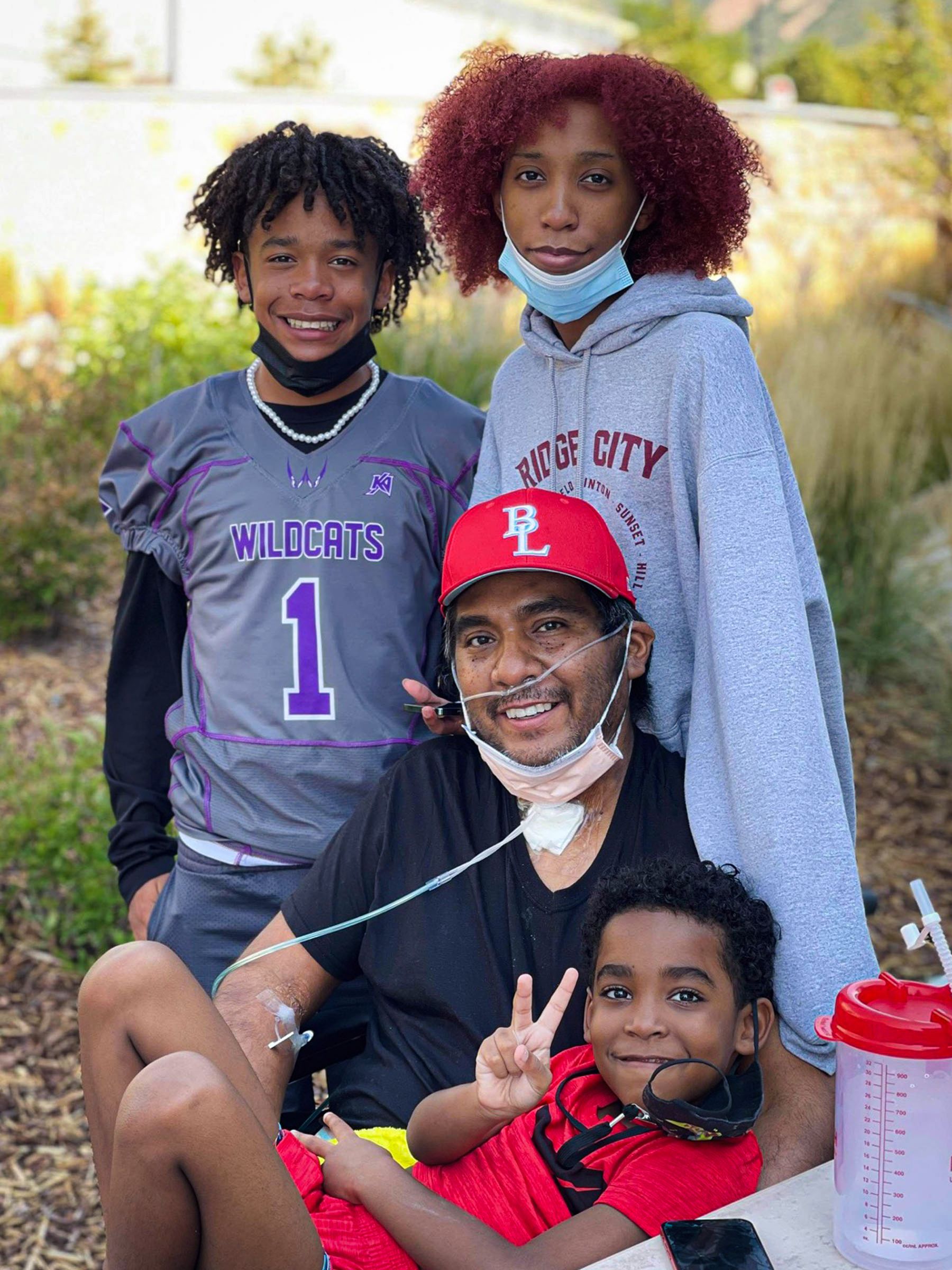 Manny with his three boys smiling at the camera.