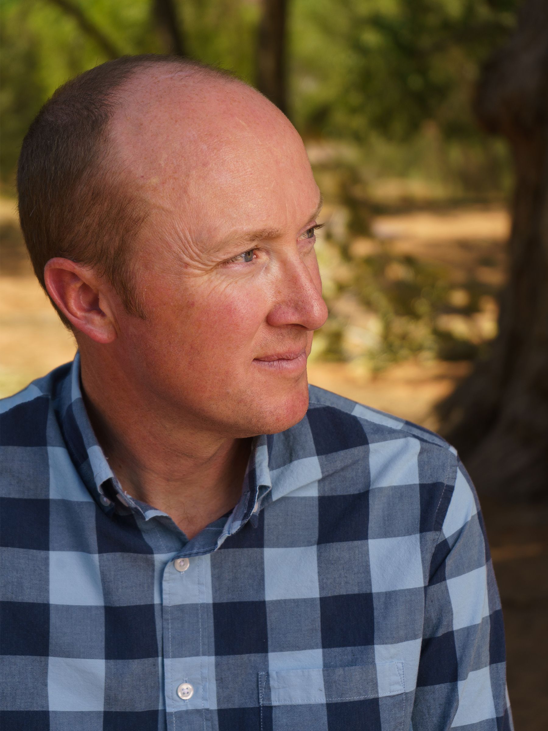 In a plaid shirt, Richard Bennett looks to his left with a slight smile.