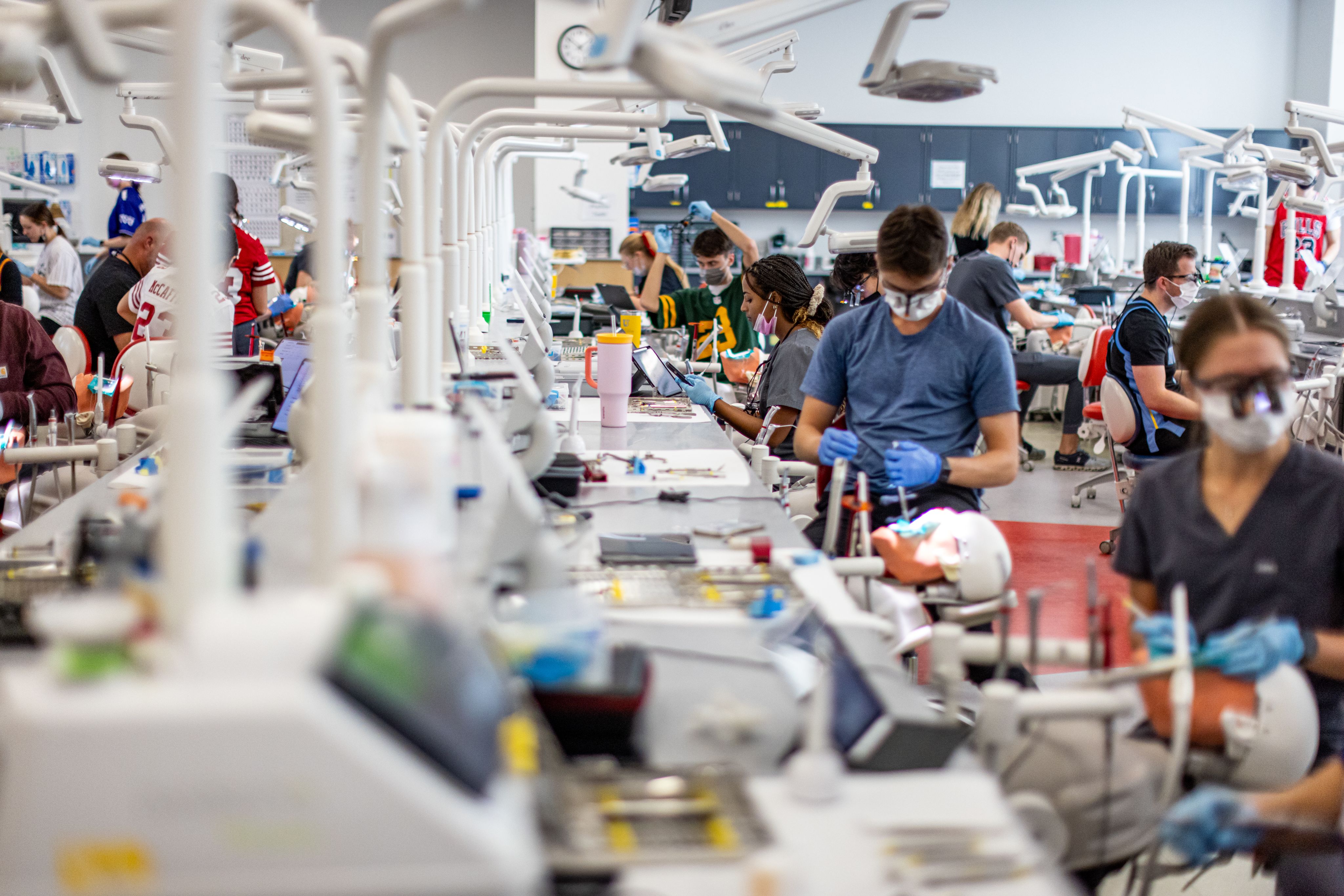 These images feature students in dental gowns and blue gloves working on artificial patients in the School of Dentistry's simulation lab. 