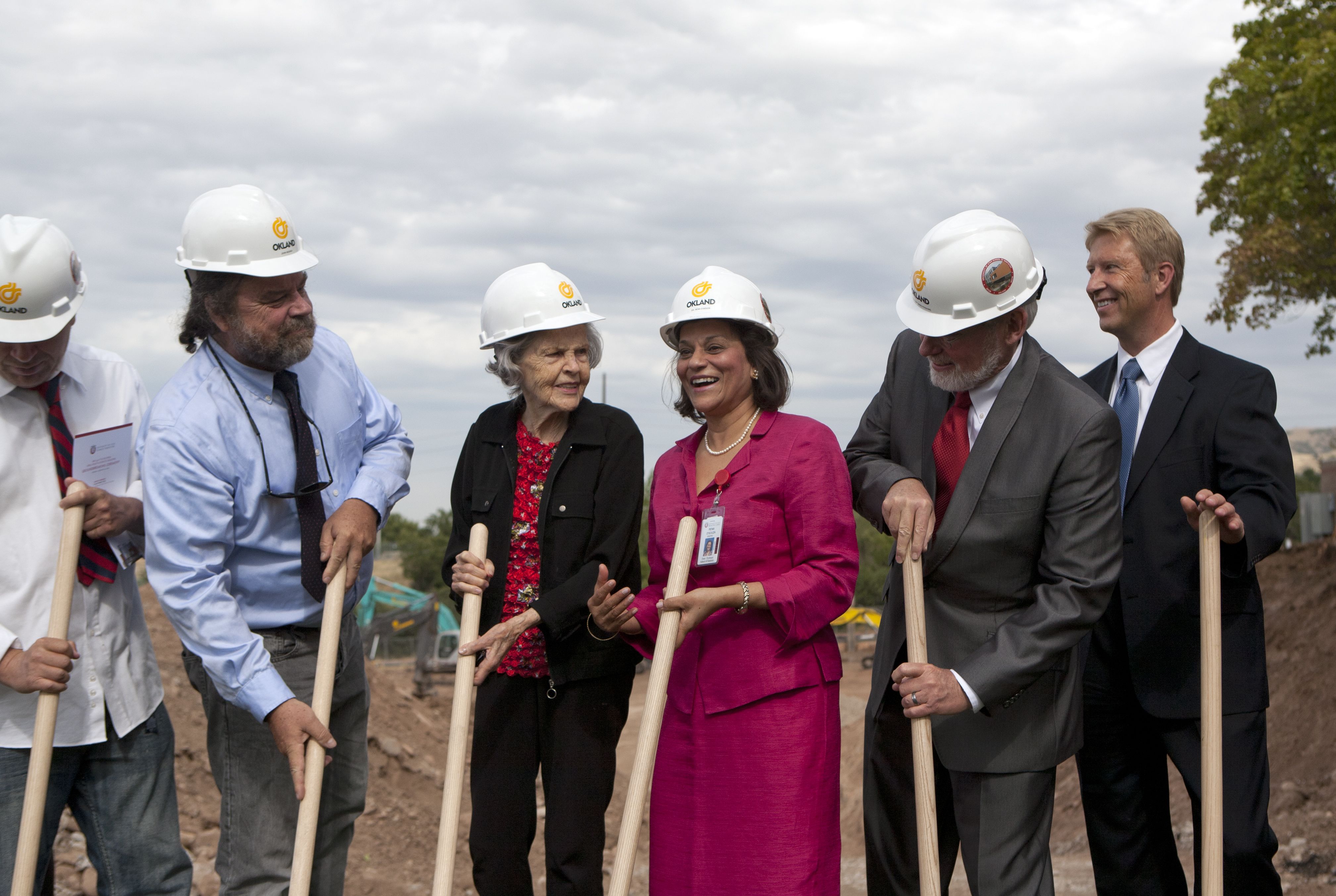 Tye Noorda in a fuschia jacket and skirt, clasping a shovel, joins the breaking-ground ceremony for the School of Dentistry building in Research Park, with Dean Hume next to her. 