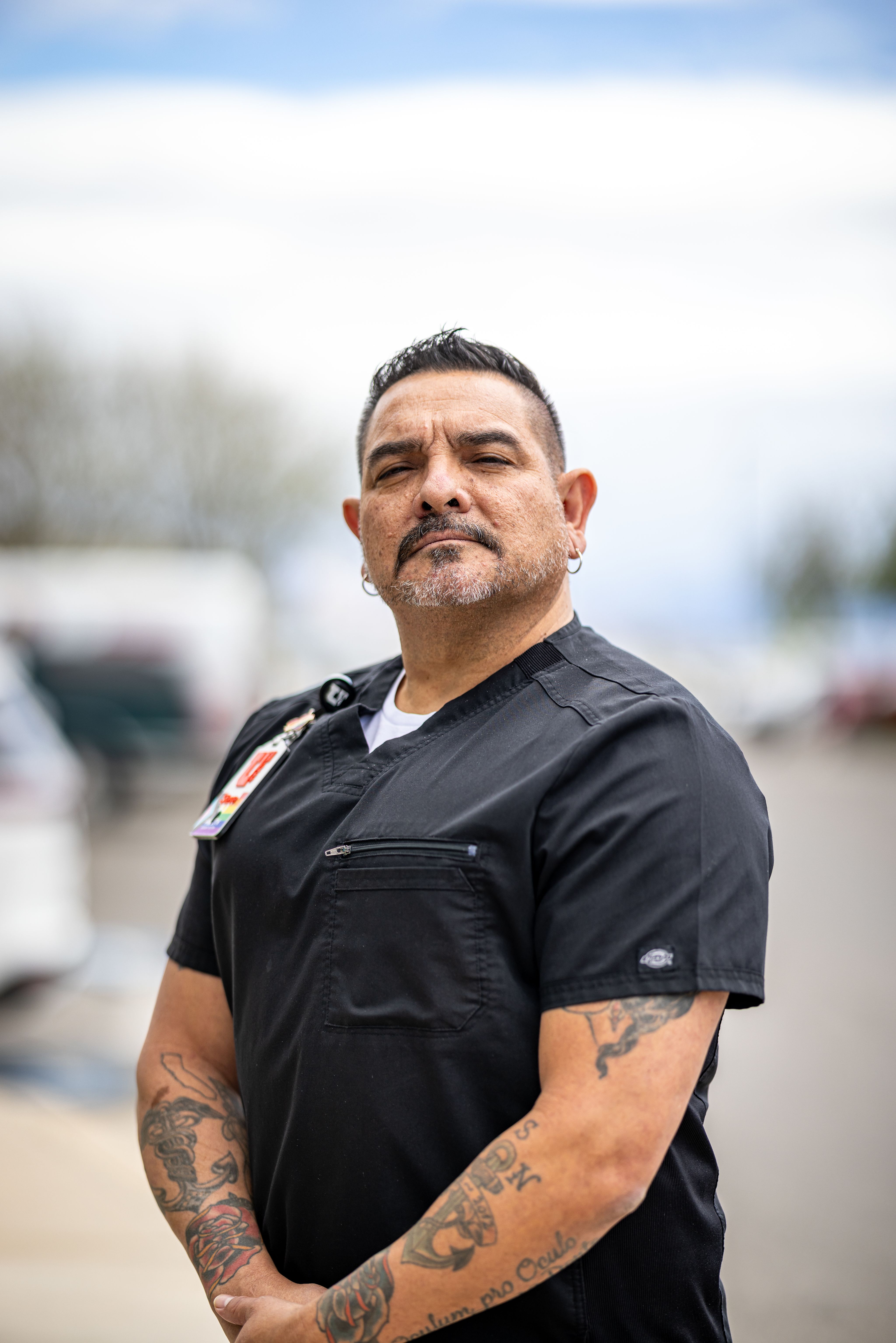 A photo of a man, clinic manager Steve Delsie, with a moustache and earrings in a dental gown