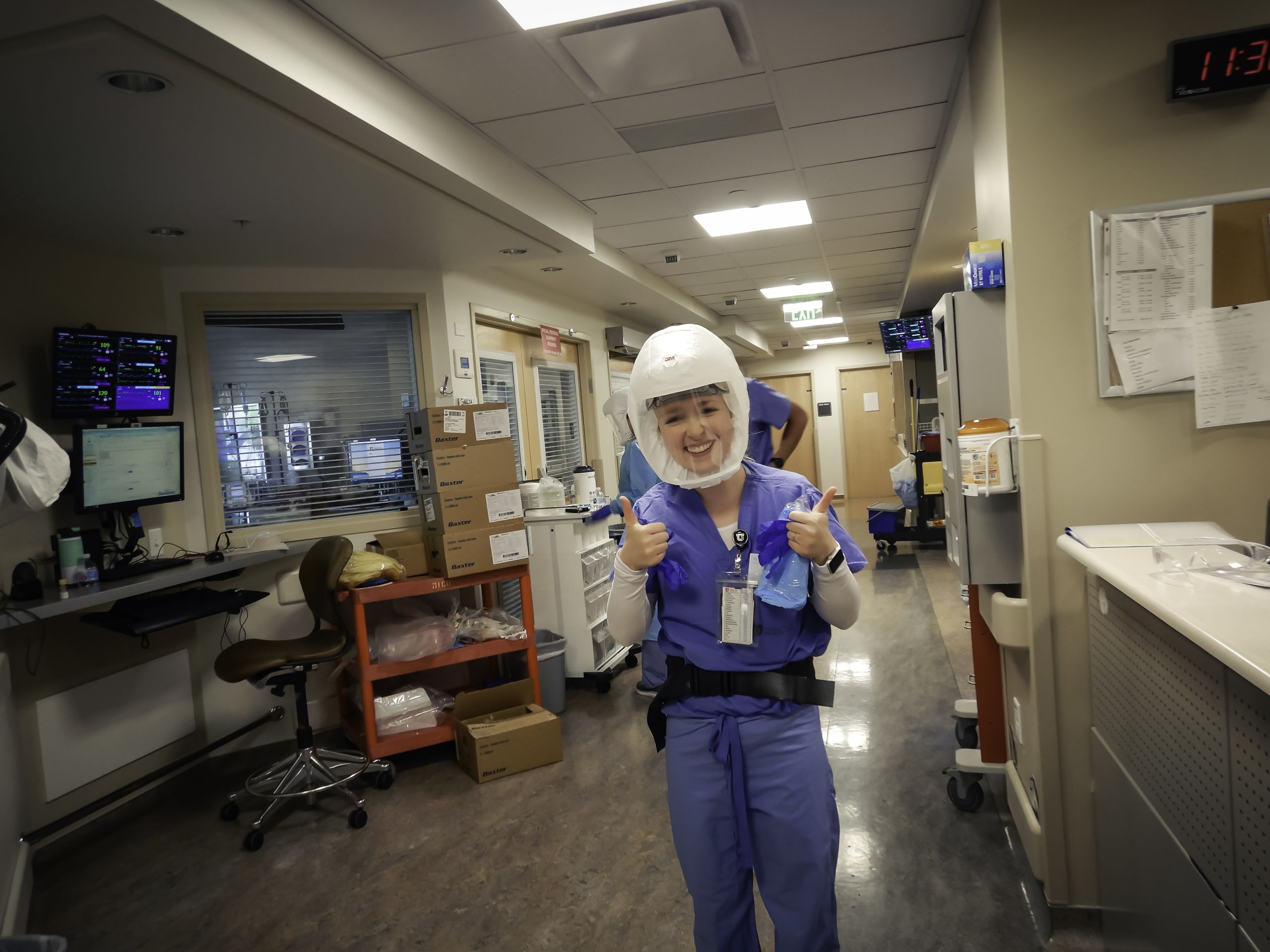 Medical ICU nurse poses in COVID-19 unit with thumbs up.